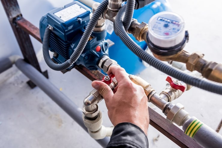 Como instalar bomba d'água: passo a passo e dicas para economizar 2 Técnico faz ajustes finais em motobomba centrífuga azul de sistema de pressurização predial com manômetro.